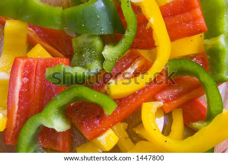 Yellow, red and green sliced peppers. Dressed with olive oil and ground pepper in glass bowl.