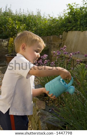 Young male watering garden. Toy watering can used to sprinkle herb garden.