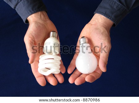 One hand holding a compact fluorescent bulb, the other an incandescent bulb, showing comparison