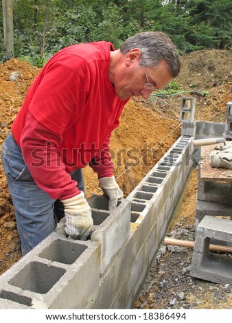 Man laying concrete block foundation wall
