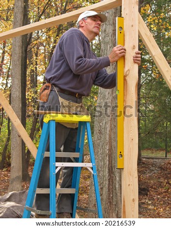 Carpenter checking level of wood framing