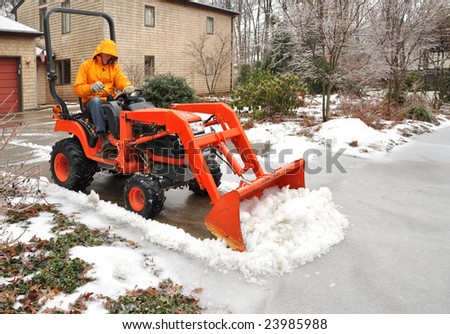 Man plowing snow and ice from a suburban driveway