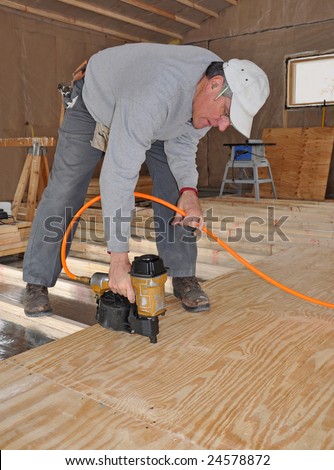 Man nailing plywood sub-floor with nail gun