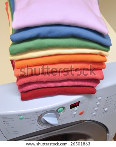 Stack of clothes in colors of the rainbow on top of front-loading washing machine