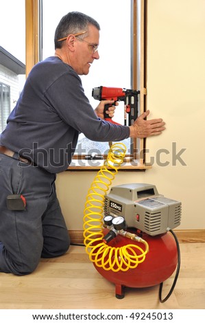 Man installing window jam extensions using nail gun powered by air compressor
