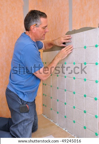 Man installing ceramic tile in shower area of bathroom