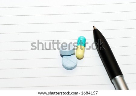 Empty blank ring, notepad, one slanted black pen on bottom right white page with pills to indicate relation with pharmaceutical industry, or metaphor for stress or work-related drug usage
