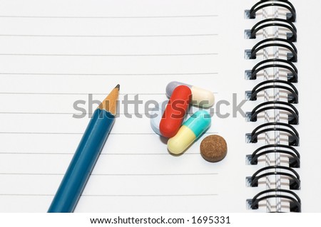 Empty blank ring, notepad, one pencil on white page with pills to indicate relation with pharmaceutical industry, or metaphor for office/school stress or work-related drug research