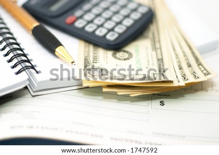 Note pad with pen, calculator and cheque book and cash. Check book. Shallow depth of field