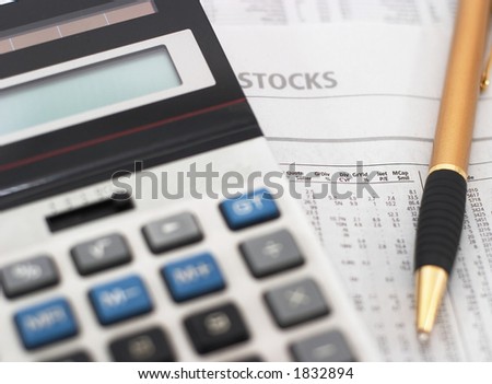 Stock market table analysis, calculator and pen indicates research and analysis, horizontal orientation, shallow depth of field, focus on text