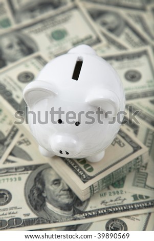 Cute piggy bank on a stack of cash. Concept of savings, and money outside of the bank.