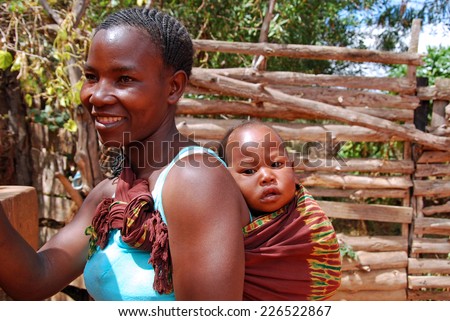 August 2014-Village of Pomerini-Tanzania-Africa-A child on the shoulders of his mother, wrapped in traditional African cloth in the Franciscan Mission of the Village of Pomerini hard hit by the AIDS
