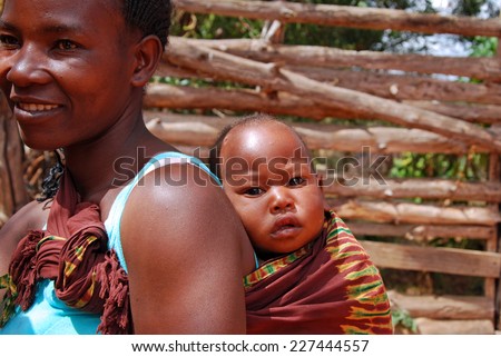 August 2014-Village of Pomerini-Tanzania-Africa-A child on the shoulders of his mother, wrapped in traditional African cloth in the Franciscan Mission of the Village of Pomerini hard hit by the AIDS