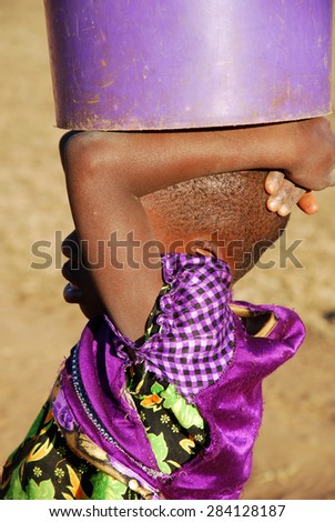 The bucket of water - Pomerini - Tanzania - Africa - A little African girl carries on his head a bucket of water
