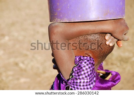 An African child with a bucket of water - Pomerini - Tanzania - Africa - A little African girl carries on his head a bucket of water