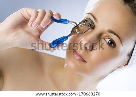 Girl using eyelash curler and makes her eyelashes wider