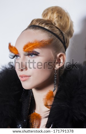 Gorgeous young model with perfect art make up and long false eyebrows made from feathers