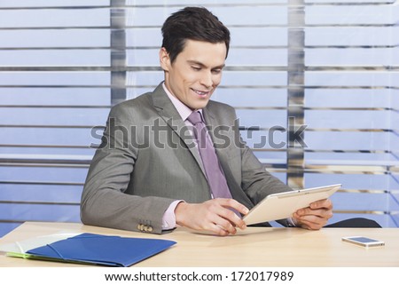 Young handsome businessman watching news on tablet pc