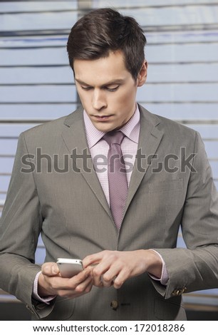 Handsome businessmen in the office checking emails on his smart phone