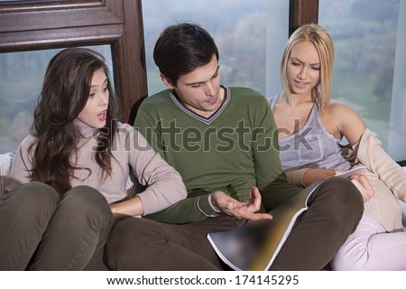 Friends sitting together on the sofa commenting news article (with path on the newspaper for easy insertions)