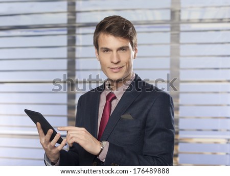 Portrait of a handsome businessmen in the office checking emails on his tablet pc