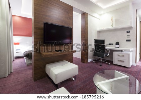 Interior of a modern hotel room with wall mounted tv in the evening