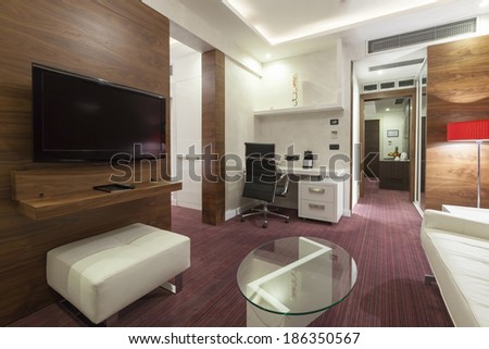 Interior of a modern hotel room with wall mounted tv in the evening