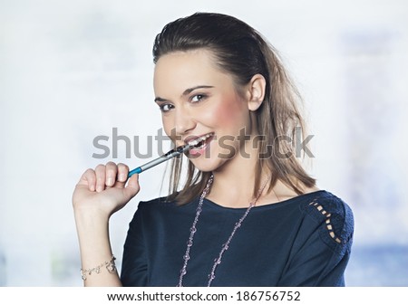 Portrait of a beautiful business women smiling, holding pen in her mouth