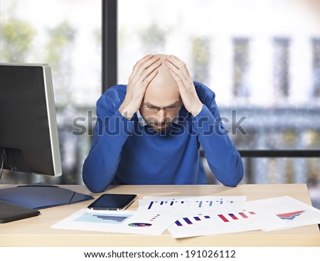 Depressed businessman in the office holding his hands on his head