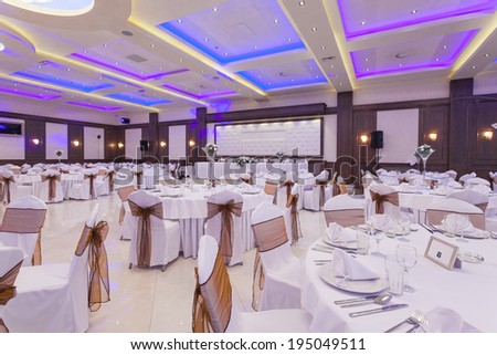 Wedding hall or other function facility with colorful ceiling lights set for fine dining