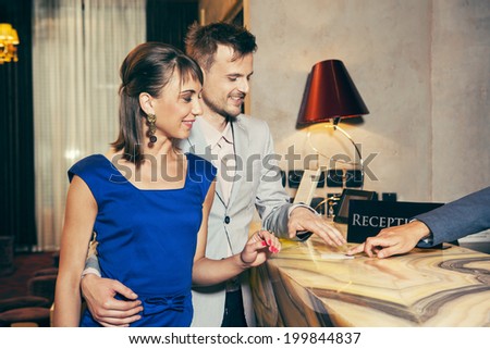 Couple doing the check-in at a luxury hotel paying by credit card