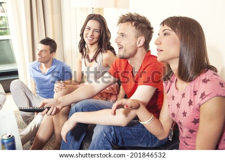 Friends eating pizza, smiling, chatting and watching tv
