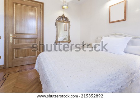 Interior of a small hotel room with antique mirror and empty picture frame