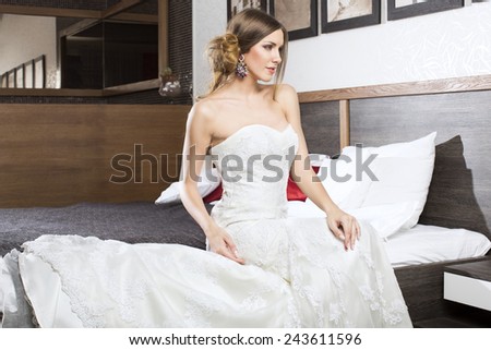 Beautiful blonde bride on a hotel bed