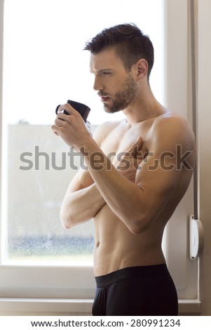 Handsome man drinking coffee by the window in the morning