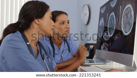 Two doctors reviewing brain scans on hospital computers