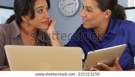 Hispanic and Black women at work in business office with laptop and tablet computer