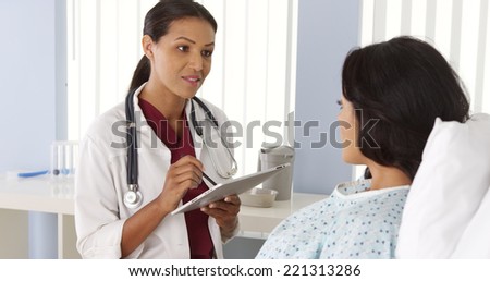African American doctor talking to Hispanic patient in bed