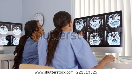 Rear view of two female doctors working together on computers