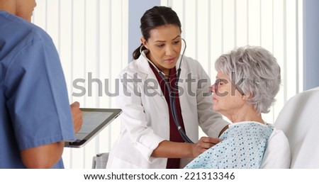 African American doctor listening to elderly patient\'s heart with stethoscope