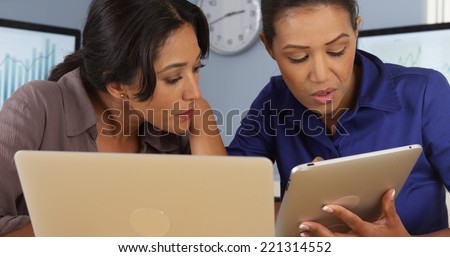 Hispanic and Black women at work in business office with laptop and tablet computer