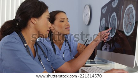 Two doctors reviewing brain scans on hospital computers