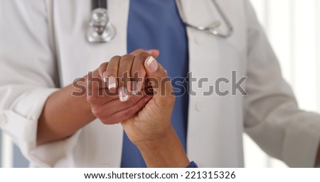 Close up of female African American doctor holding patient\'s hand