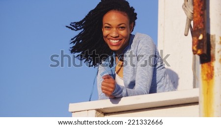 Happy black woman leaning on rail smiling