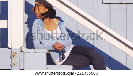 Happy black woman sitting on outdoor stairs smiling