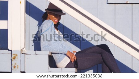 Happy black woman sitting on outdoor stairs smiling