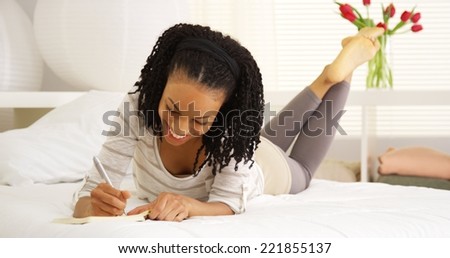 Happy black woman writing in journal
