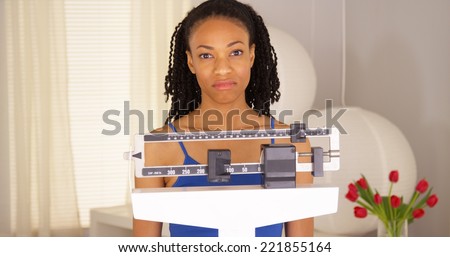 Disappointed black woman checks weight and walks away