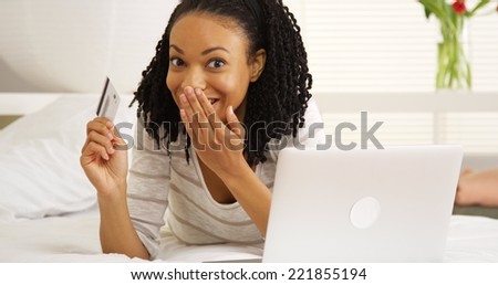 Happy African woman smiling with laptop and credit card