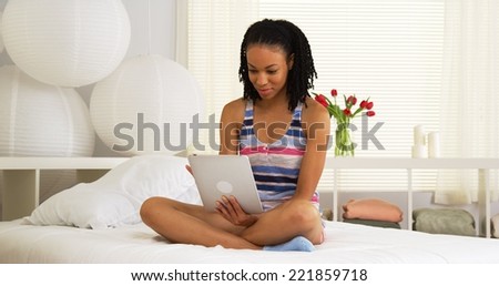 African woman sitting on bed using tablet
